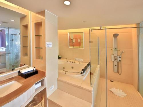 XinhuiにあるCountry Garden Phoenix Hotel Xinhui Jiangmenの浴槽とガラスのシャワー付きのバスルーム