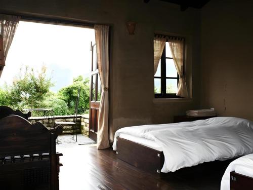 ein Schlafzimmer mit zwei Betten und einem großen Fenster in der Unterkunft Hananoie - A Permaculture Resort in Pokhara