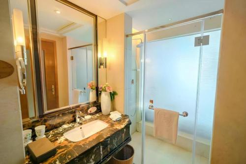 a bathroom with a sink and a glass shower at King Century Hotel in Zhongshan