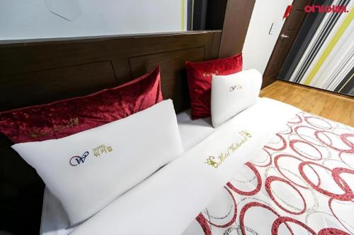 a bed with red and white pillows on it at Chuncheon World Hotel in Chuncheon