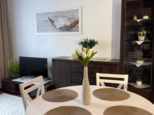 a white vase with flowers sitting on a table at A&M Apartments - apartment Prostejovska in Prešov