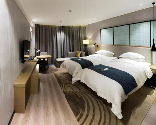a hotel room with two beds and a television at Echarm Hotel Nanchang Hongcheng Wangfujing in Taohua