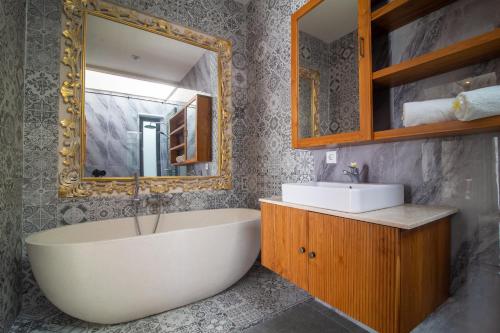 a bathroom with a tub and a sink and a mirror at Villa Dewi 3 in Ubud