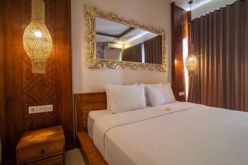 a bedroom with a white bed and a mirror at Villa Dewi 3 in Ubud