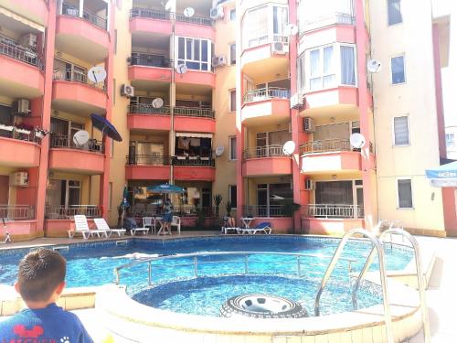 a boy standing next to a swimming pool in front of a building at One Sunny Home in Sunny Beach in Sunny Beach
