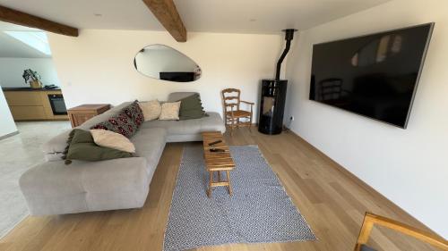 a living room with a couch and a television at La ferme Le Clos de la Becque in Muncq-Nieurlet