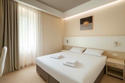 a bedroom with a white bed with two towels on it at Guest House Neho in Cres