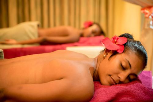 a woman with a flower in her hair laying on a bed at Oasis Hotel Restaurant & Spa in Grand'Anse Praslin