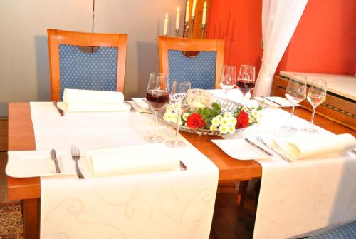 a table with glasses of wine and a bowl of flowers at Weingasthof Zum weißen Roß in Osthofen