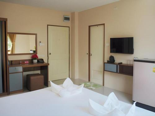 a hotel room with a bed with white sheets and a television at Regent Room Hotel in Suratthani