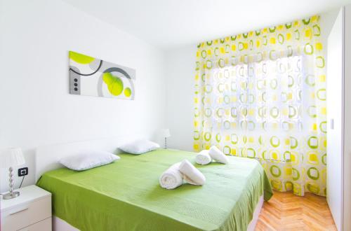 a bedroom with a green bed with towels on it at Apartments Nicole in Pula