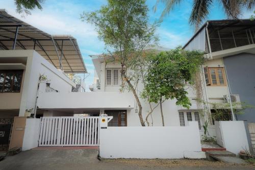 a white house with a white fence in front of it at Cozy Studio - Panampilly Nagar in Cochin