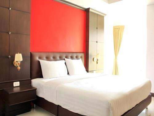 una camera da letto con un letto grande con una parete rossa di I-Yaris Boutique Resort a Khon Kaen