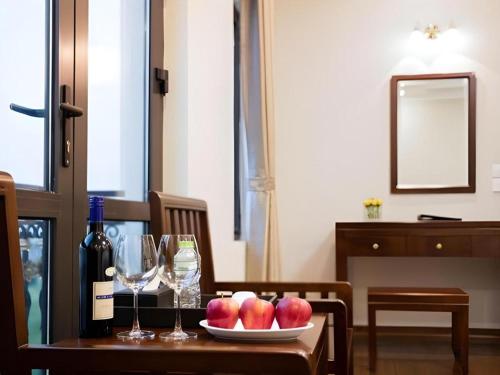 a table with a plate of apples and wine glasses at Binh Anh Hotel Hanoi in Hanoi
