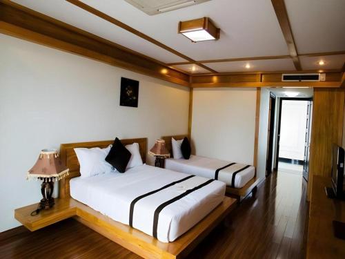 a bedroom with two beds and two lamps at Kaya Hotel in Phước Hậu