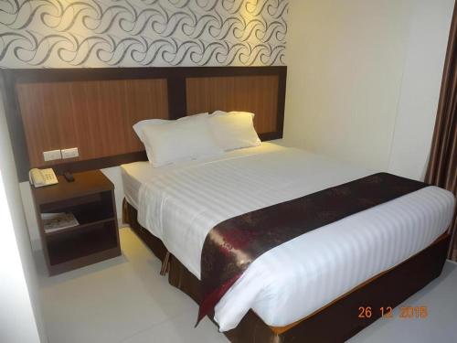 a bedroom with a large bed and a night stand at Hotel Grand Permata Hati in Banda Aceh