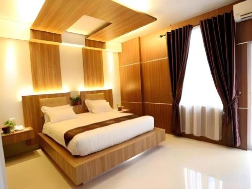 a bedroom with a large bed with a large window at Hotel Grand Permata Hati in Banda Aceh