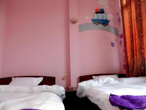 two beds in a pink room with a train on the wall at Halong Happy Hostel in Ha Long
