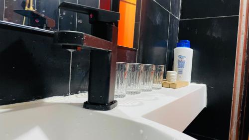a bathroom sink with a faucet and glasses on it at The house where time is wasted under the road in Chongqing