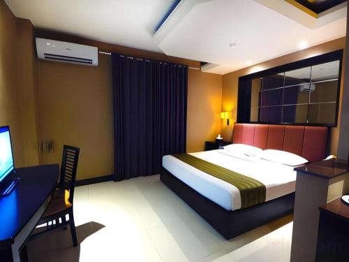 a bedroom with a bed and a desk and a television at Tematik Hotel Pluit in Jakarta