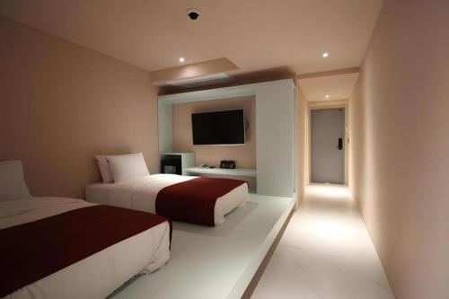 a bedroom with two beds and a flat screen tv at Bobo Hotel Hongdae in Seoul