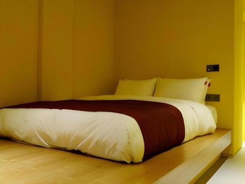 a bedroom with a large bed with white and brown sheets at Bobo Hotel Hongdae in Seoul