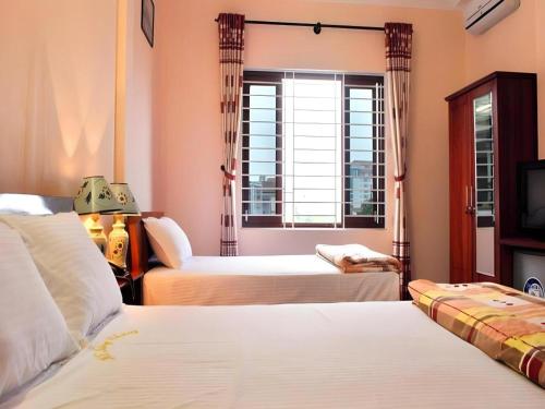 a hotel room with two beds and a window at Hong Thang Hotel in Thôn Lại Thê