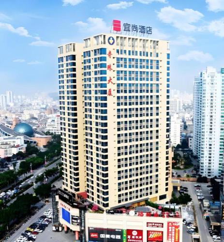 a tall white building with a sign on top of it at Echarm Hotel Beihai Railway Station in Beihai
