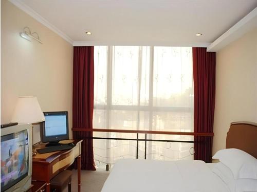 a bedroom with a bed and a desk with a computer at Out Sky Hotel in Huizhou