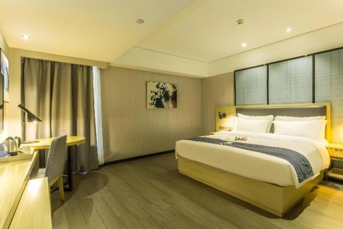 a hotel room with a bed and a desk at Echarm Hotel Beihai Railway Station in Beihai