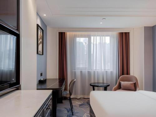 a hotel room with a bed and a desk and a window at Jinjiang Metropolo Hotel Nanjing Confucius Temple Branch in Nanjing