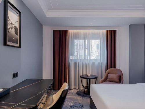 a hotel room with a bed and a desk and a window at Jinjiang Metropolo Hotel Nanjing Confucius Temple Branch in Nanjing