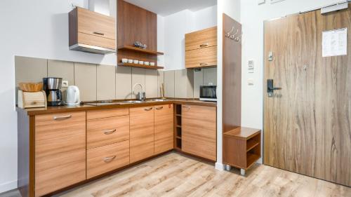 a kitchen with wooden cabinets and a wooden door at Olympic Park I, Sun & Snow in Kołobrzeg