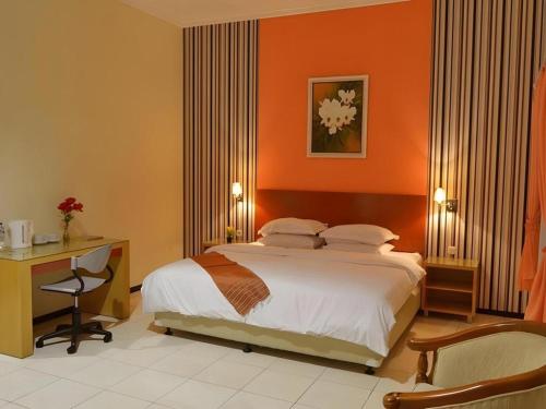 a bedroom with a bed with an orange wall at Hotel Kings Kudus in Kudus