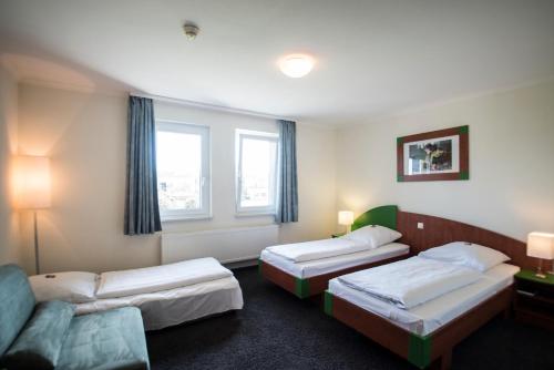 a hotel room with two beds and a couch at EuroHotel Günzburg in Günzburg