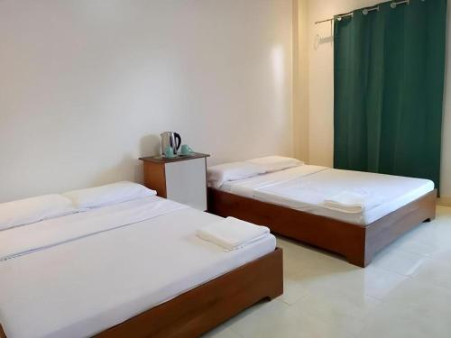 two beds in a room with a green curtain at Joaquim's Lodge in Luka