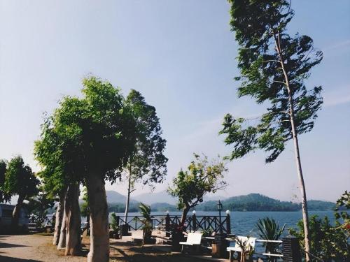 a row of trees sitting next to a body of water at Rim Kaeng resort in Phetchaburi
