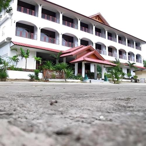 a large white building with palm trees in front of it at Rim Kaeng resort in Phetchaburi
