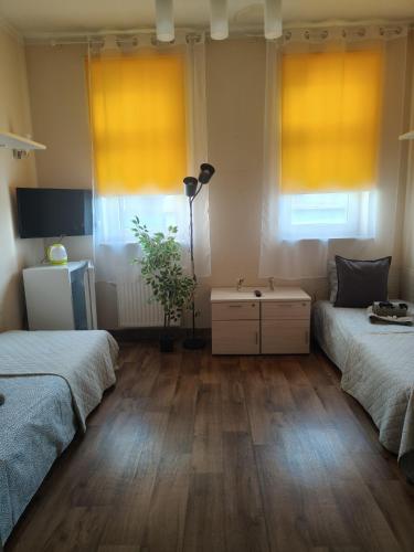 a room with two beds and a table and two windows at Pokoje Gościnne Rozbark in Bytom