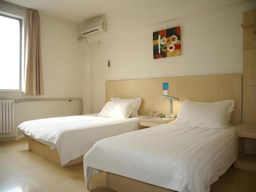 a hotel room with two beds and a window at Jinjiang Inn Qingdao Development Zone Jinggangshan Rd. in Huangdao