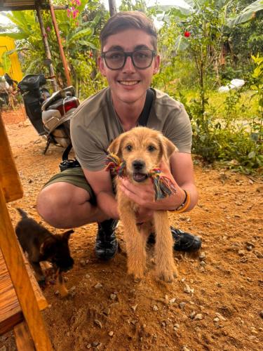 a man holding a dog with a toy in its mouth at Vuglamping in Hue