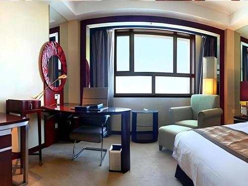 a hotel room with a bed and a desk and a bedroom at Dunhuang Grand Soluxe Hotel in Dunhuang