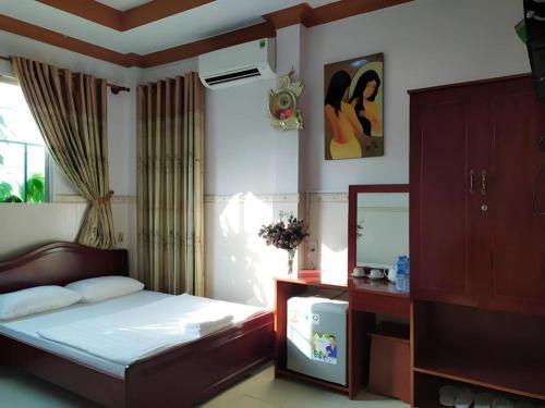 a bedroom with a bed and a dresser and a mirror at Quang Sang Hotel Can Tho in Can Tho
