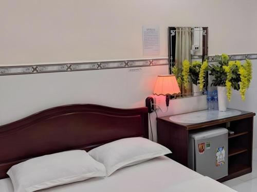 a bed with a wooden headboard and a table with a mirror at Quang Sang Hotel Can Tho in Can Tho