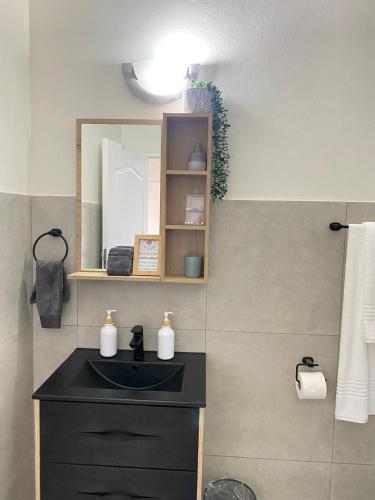 a bathroom with a black sink and a mirror at Nunu's Self Catering Apartment in Paarl