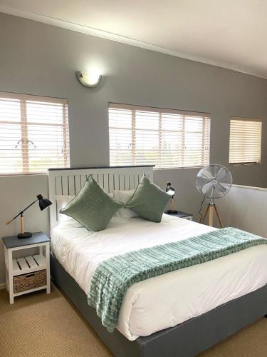 a bedroom with a bed with green pillows and a fan at Nunu's Self Catering Apartment in Paarl