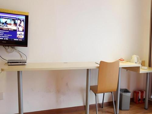 a desk with a computer on top of it with a chair at 7 Days Inn Chengdu Huayang Metro Station Binfen Plaza in Chengdu