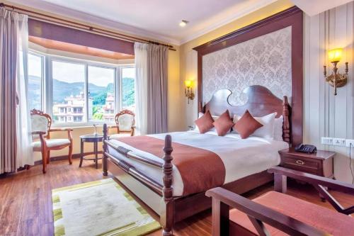 Un dormitorio con una cama grande y una ventana grande. en Da Yatra Courtyard Hotel & Resort, en Pokhara