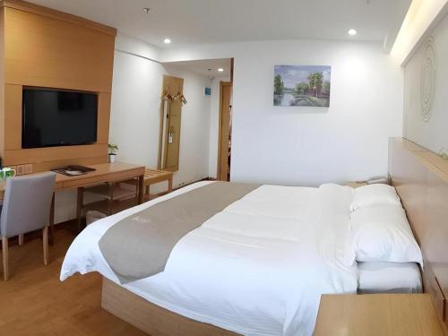 a bedroom with a bed and a desk and a television at GreenTree Inn Anqing Qianshan County Sunshine City Express Hotel in Qianshan