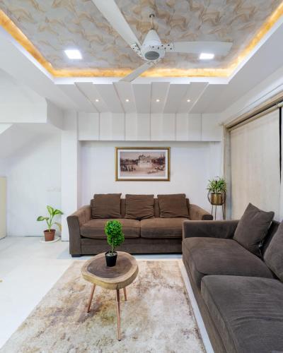 a living room with two brown couches and a table at Pearl Palace 4-Bedrooms Villa by Spacez with Private Theatre & Terrace in Mumbai
